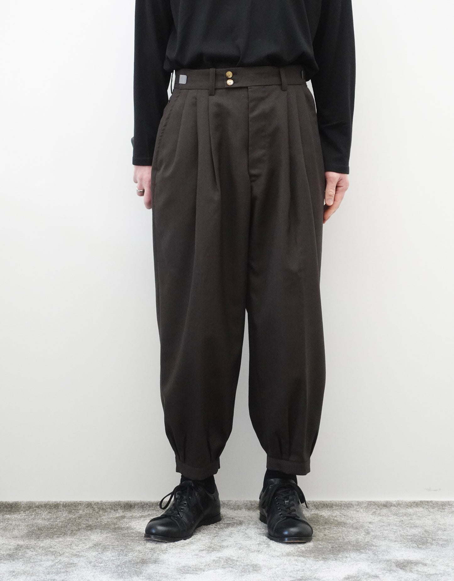VOUILLON(ヴイヨン)のTriple Tuck Harlem Slacks - DARK BROWN(トリプルタックハーレムスラックス)。腰元の3タックによるボリューム感と、裾にかけて絞られたハーレムシルエットが特徴のブラック・コクーンシルエットパンツ。色味とシルエットがわかる着用正面画像。