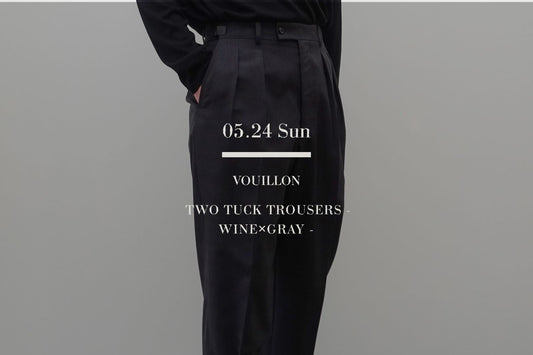 VOUILLONのTWO TUCK TROUSERS（WINE×GRAY）を着用した男性の腰回りのクローズアップ。黒の長袖トップスをタックインし、スッキリとした端正な印象を与えるインタック（2タック）仕様のディテールとアジャスターベルトを強調したミニマルなスタイリング。中央に「05.24 Sun VOUILLON TWO TUCK TROUSERS - WINE×GRAY -」の白いブランドロゴテキスト。