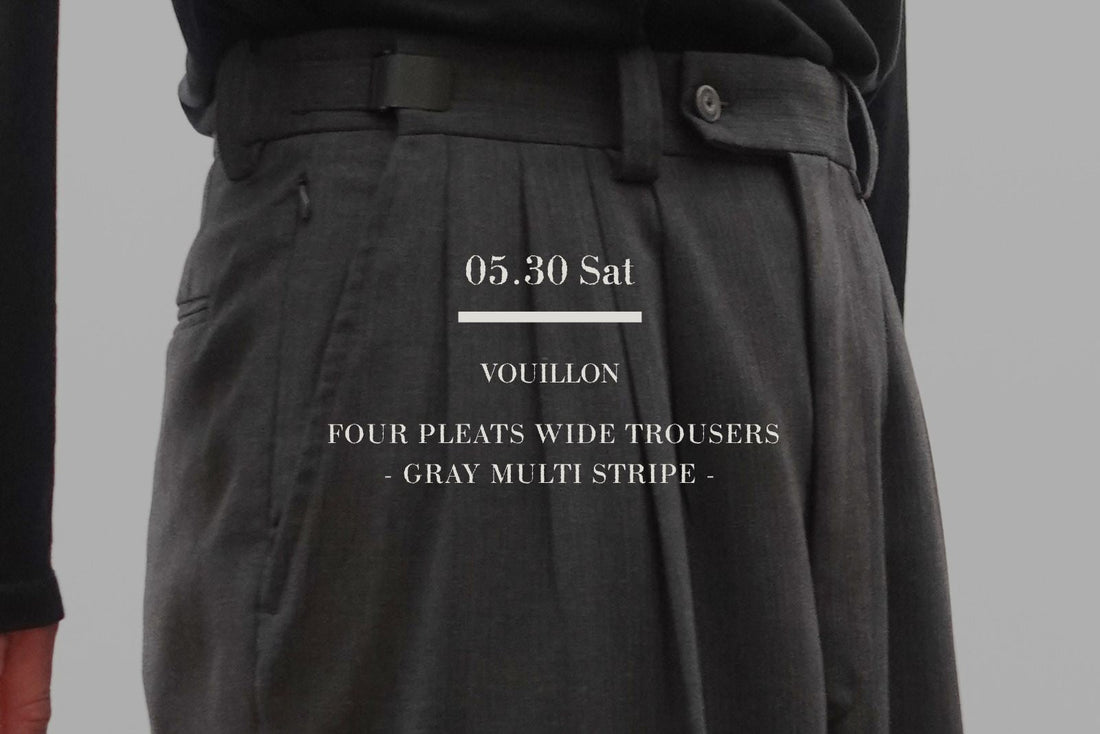 VOUILLONのFOUR PLEATS WIDE TROUSERSのGRAY MULTI STRIPEを着用した男性の腰回りクローズアップ。黒のトップスをタックインし、美しく立体的な4プリーツの折り込みと、ウエスト位置を18センチ可変できる調整アジャスターベルトの機能美を強調したミニマルなスタイリング。中央に白いブランドロゴテキスト。