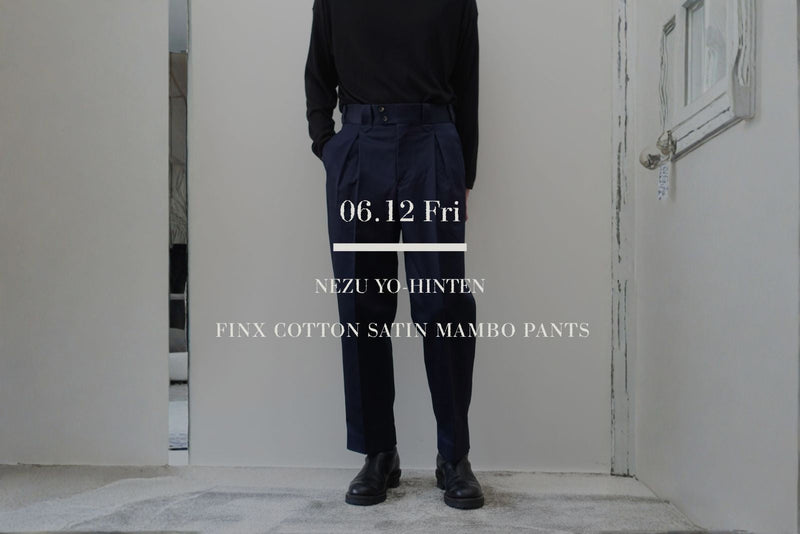 VOUILLON（ヴイヨン）マガジンのトップ画像。NEZU YO-HINTEN（根津洋品店）のフィンクスコットンサテン マンボパンツ（Mambo Pants）。上品な光沢を持つネイビーのサテン生地と、深いタックによるテーパードシルエットが特徴的なボトムスの正面全身スタイリングに、「06.12 Fri」の文字を重ねたグラフィック。