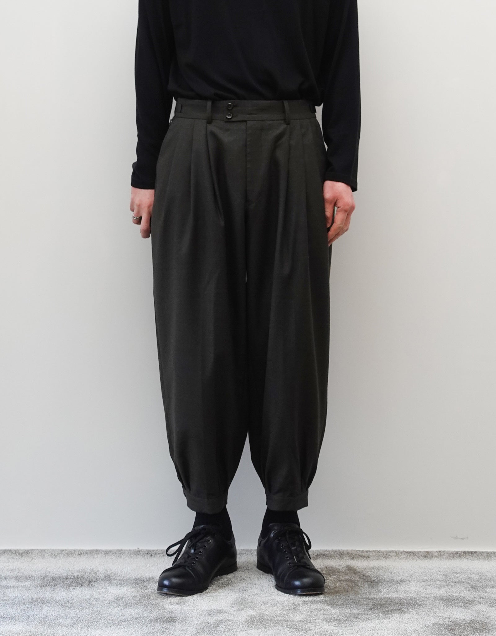 VOUILLON（ヴイヨン）のTriple Tuck Harlem Slacks - DARK OLIVE（トリプルタックハーレムスラックス）。腰元の3タックによるボリューム感と、裾にかけて絞られたハーレムシルエットが特徴のダークオリーブ・ワイドパンツ。シックでモードな上品な印象。正面の着用画像。