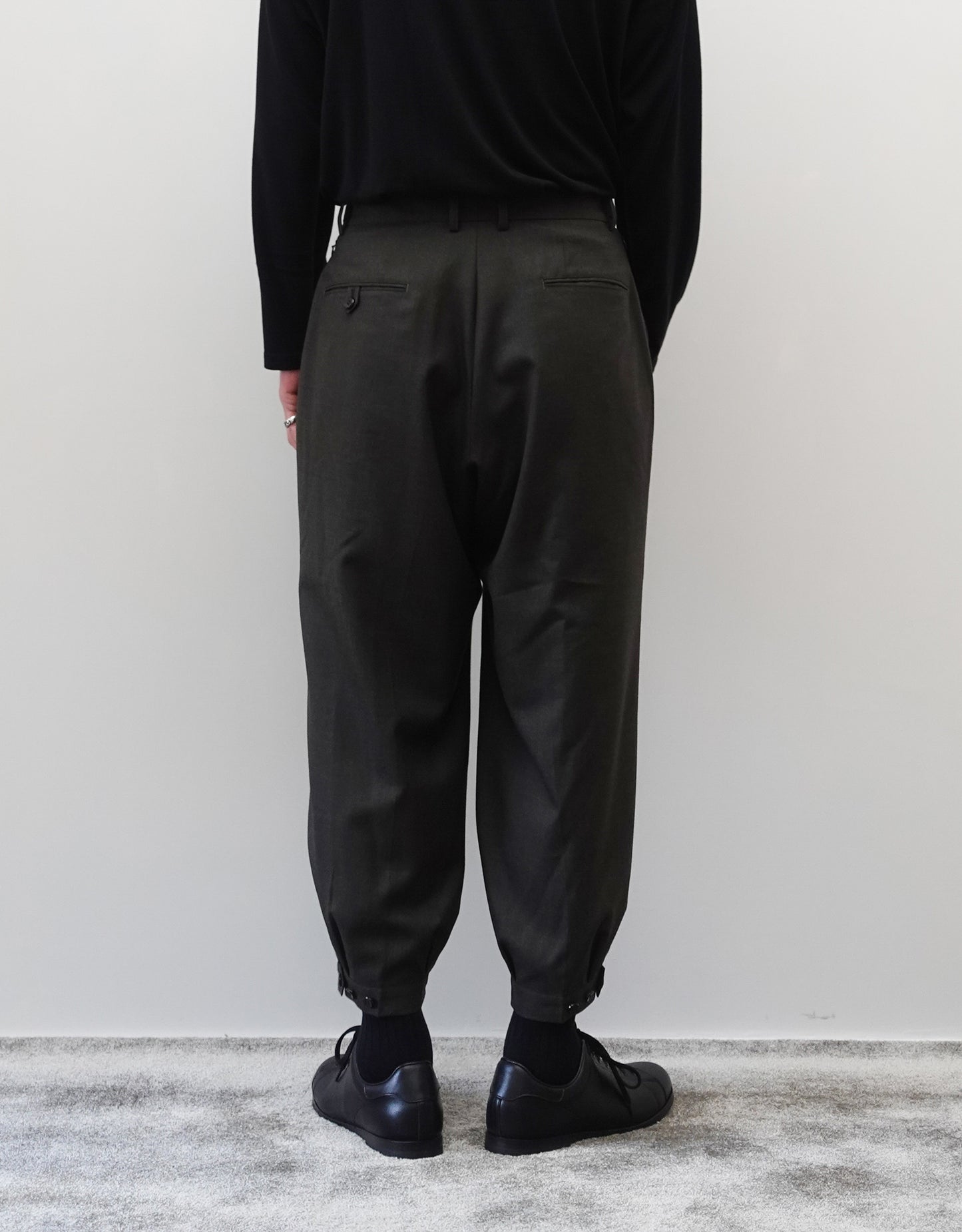 VOUILLON（ヴイヨン）のTriple Tuck Harlem Slacks - DARK OLIVE（トリプルタックハーレムスラックス）。腰元の3タックによるボリューム感と、裾にかけて絞られたハーレムシルエットが特徴のダークオリーブ・ワイドパンツ。シックでモードな上品な印象。胸から下の背面の着用画像。