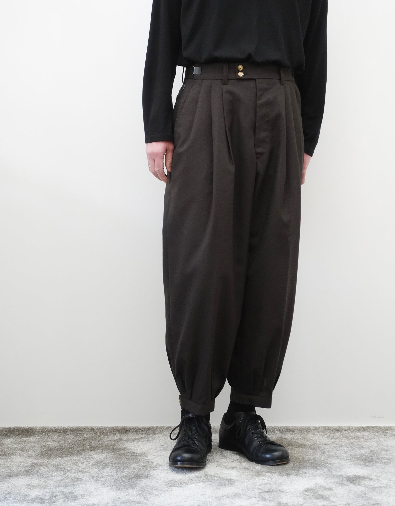 VOUILLON（ヴイヨン）のTriple Tuck Harlem Slacks - DARK BROWN（トリプルタックハーレムスラックス）。腰元の3タックによるボリューム感と、裾にかけて絞られたハーレムシルエットが特徴のブラック・ワイドパンツ。色味とシルエットがわかる着用正面画像。