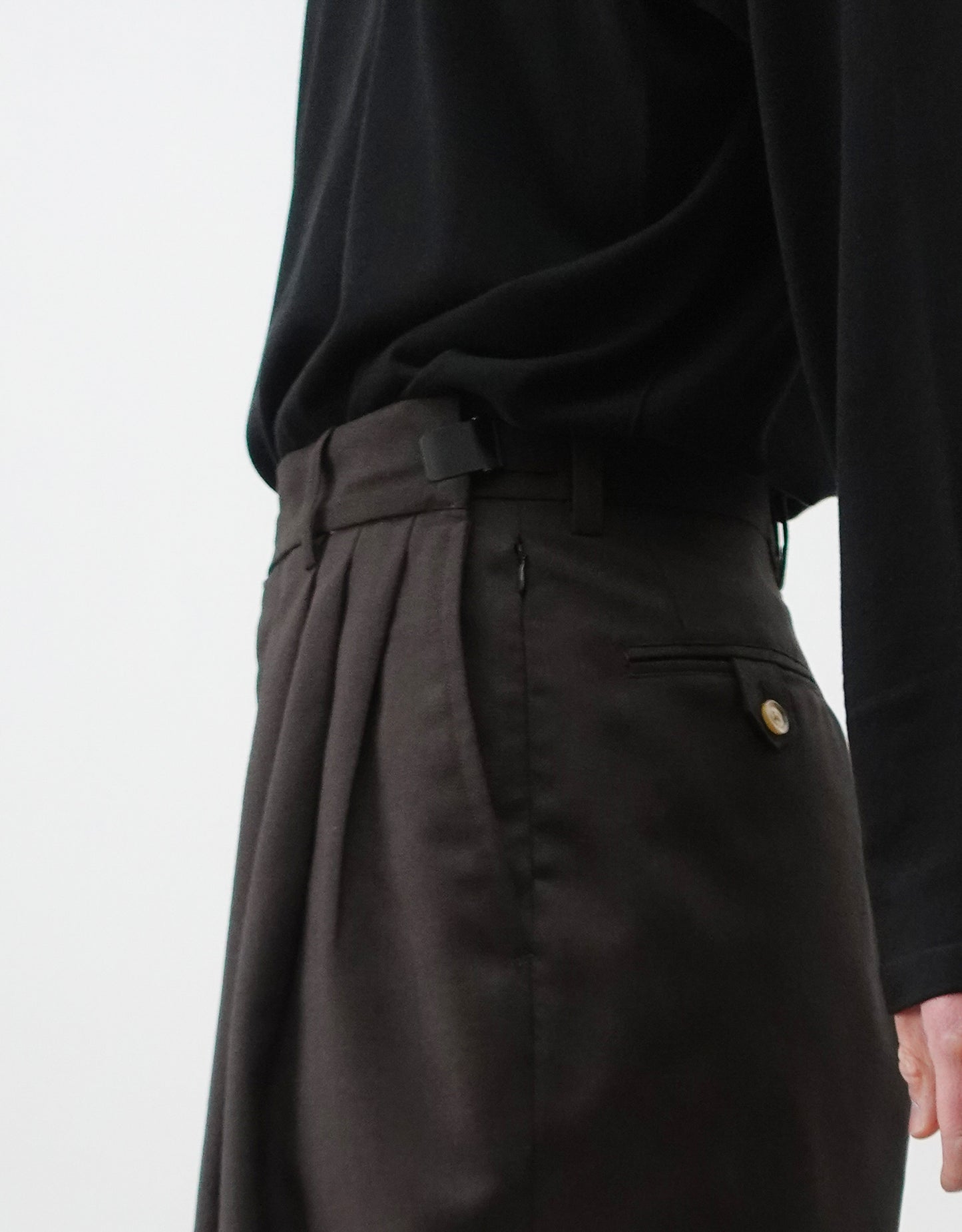 VOUILLON（ヴイヨン）のTriple Tuck Harlem Slacks - DARK BROWN（トリプルタックハーレムスラックス）。腰元の3タックによるボリューム感と、裾にかけて絞られたハーレムシルエットが特徴のブラック・ワイドパンツ。色味とウエストのアジャスターがわかる寄り画像。
