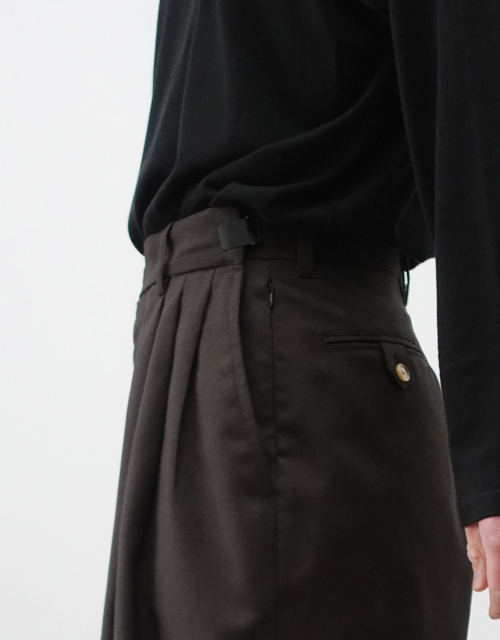 VOUILLON（ヴイヨン）のTriple Tuck Harlem Slacks - DARK BROWN（トリプルタックハーレムスラックス）。腰元の3タックによるボリューム感と、裾にかけて絞られたハーレムシルエットが特徴のブラック・ワイドパンツ。色味とウエストのアジャスターがわかる寄り画像。