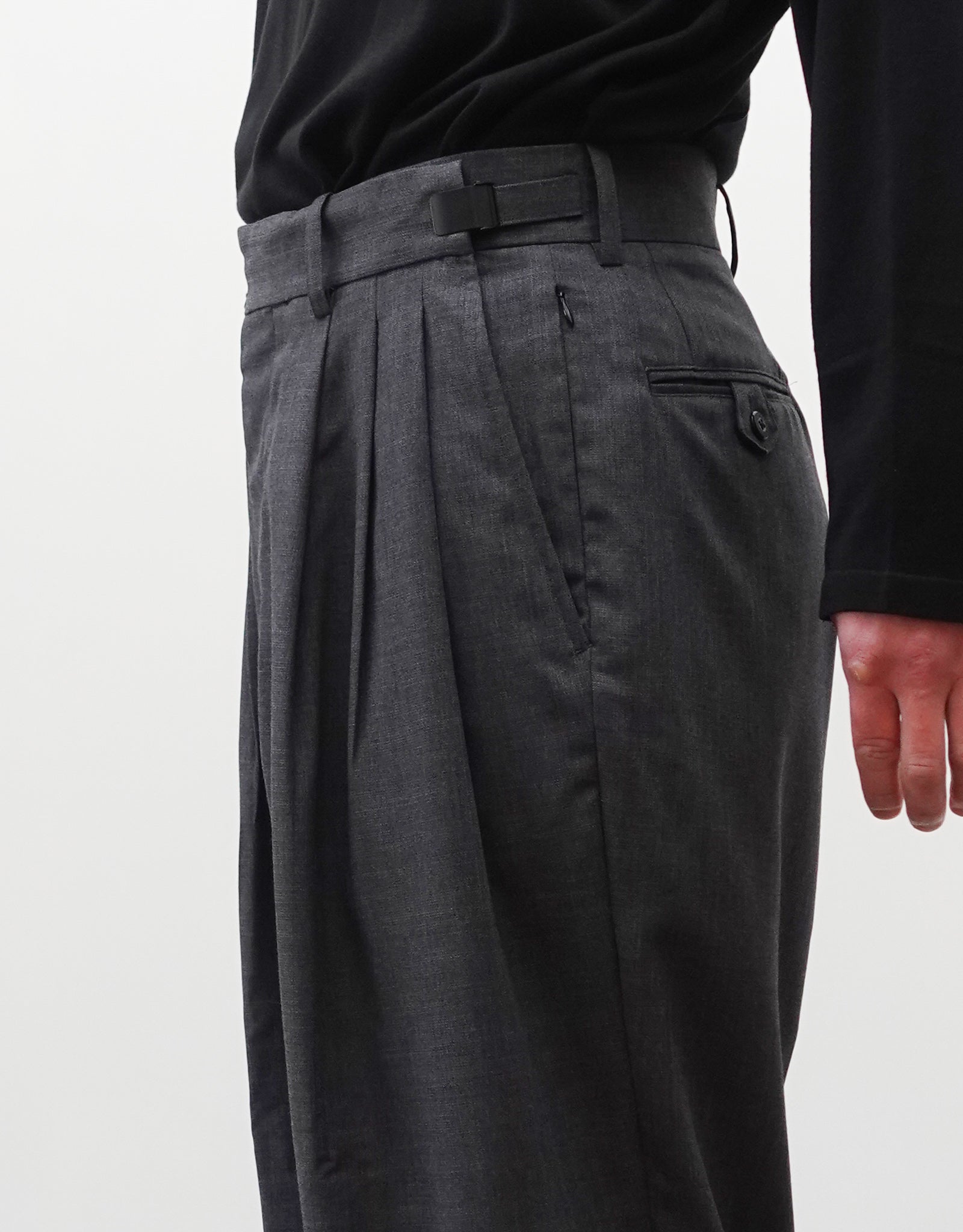VOUILLON（ヴイヨン）のTriple Tuck Harlem Slacks - DARK GRAY（トリプルタックハーレムスラックス）。腰元の3タックによるボリューム感と、裾にかけて絞られたハーレムシルエットが特徴のダークグレー・ワイドパンツ。ウエストのアジャスターを最小にした着用画像。