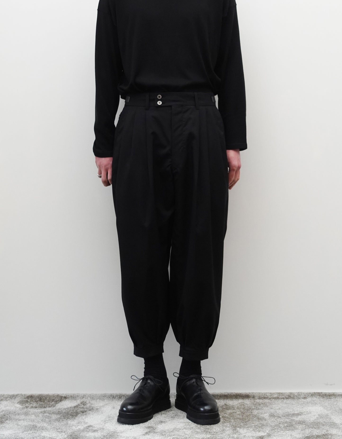 VOUILLON（ヴイヨン）のTriple Tuck Harlem Slacks - Black（トリプルタックハーレムスラックス）。腰元の3タックによるボリューム感と、裾にかけて絞られたハーレムシルエットが特徴のブラック・ワイドパンツ。モードなオールブラックのスタイリング。