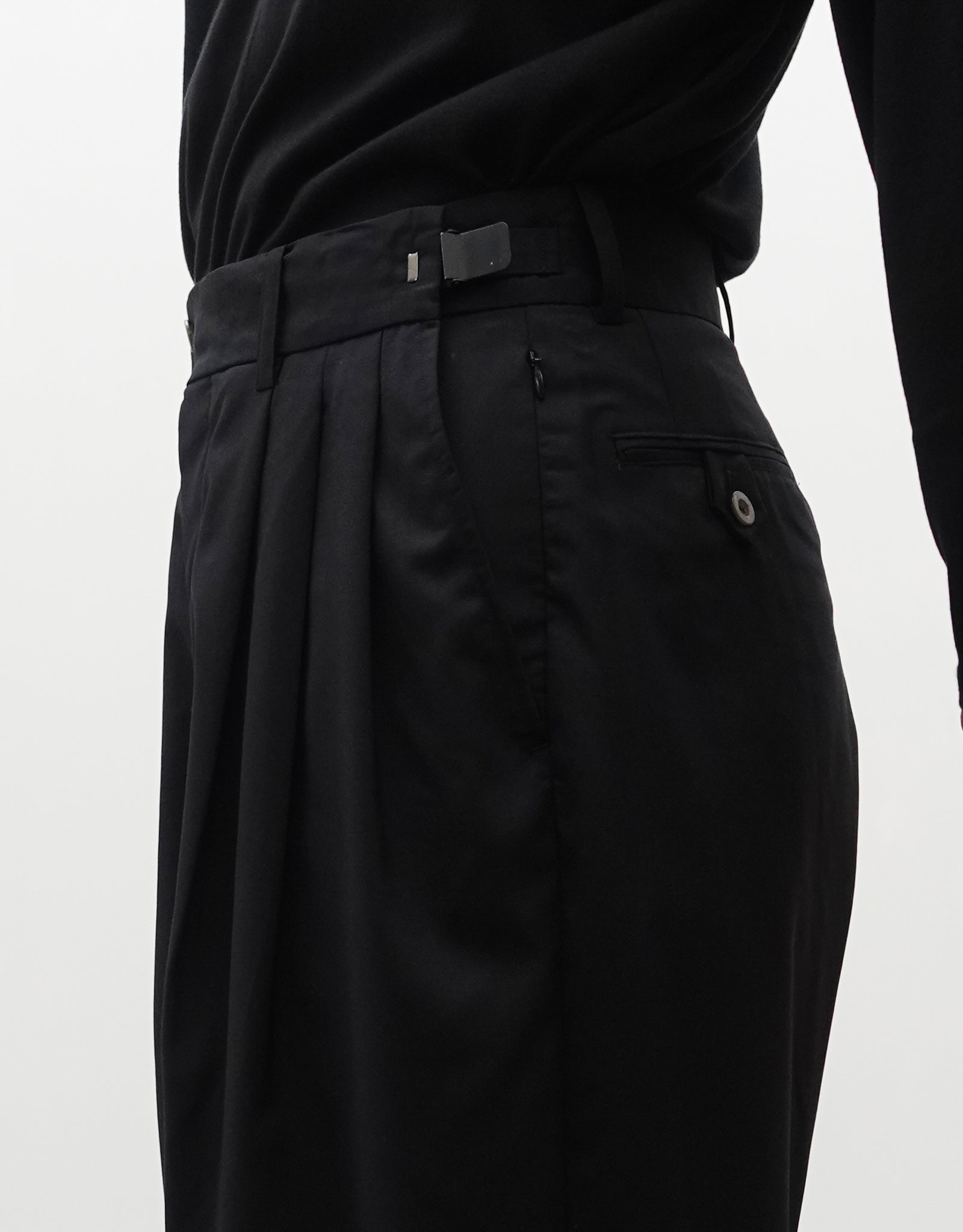 VOUILLON（ヴイヨン）のTriple Tuck Harlem Slacks - Black（トリプルタックハーレムスラックス）。腰元の3タックによるボリューム感と、裾にかけて絞られたハーレムシルエットが特徴のブラック・コクーンシルエットのパンツ。右斜めからウエスト寄りでウエストのアジャスター紹介画像。