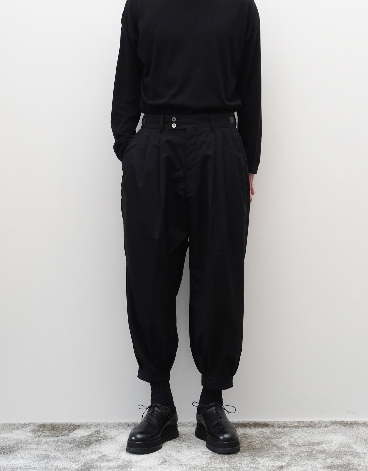 VOUILLON（ヴイヨン）のTriple Tuck Harlem Slacks - Black（トリプルタックハーレムスラックス）。腰元の3タックによるボリューム感と、裾にかけて絞られたハーレムシルエットが特徴のブラック・コクーンシルエットのパンツ。シルエットがわかる正面撮影。