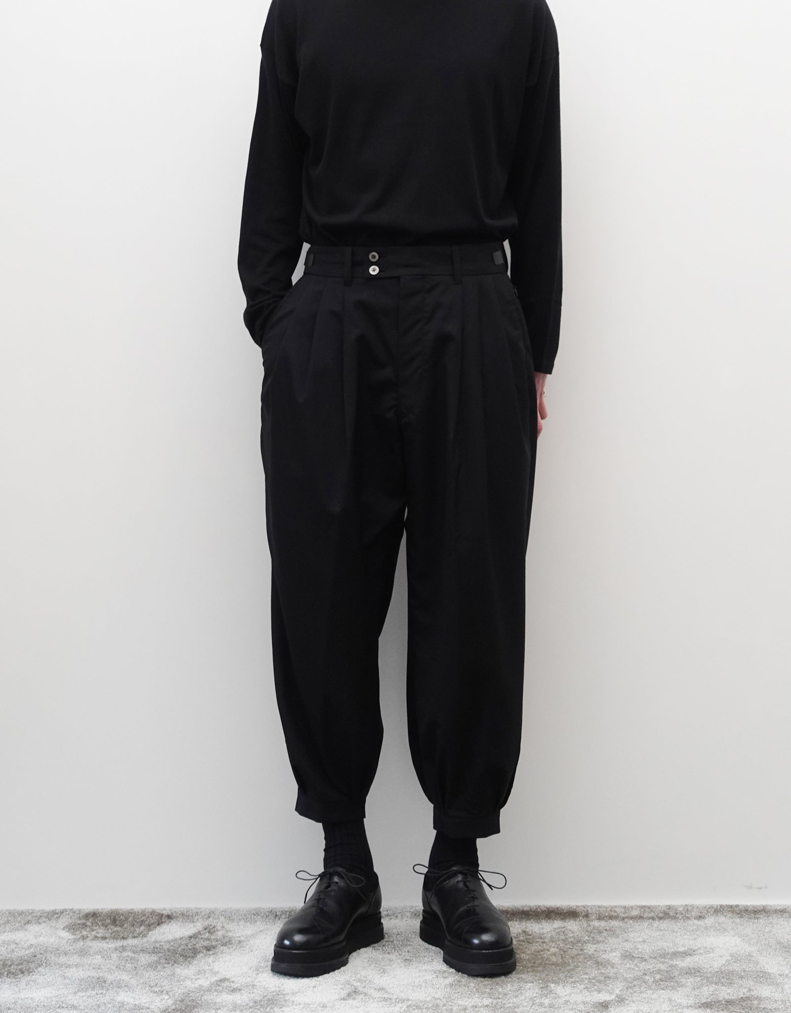 VOUILLON（ヴイヨン）のTriple Tuck Harlem Slacks - Black（トリプルタックハーレムスラックス）。腰元の3タックによるボリューム感と、裾にかけて絞られたハーレムシルエットが特徴のブラック・コクーンシルエットのパンツ。シルエットがわかる正面撮影。