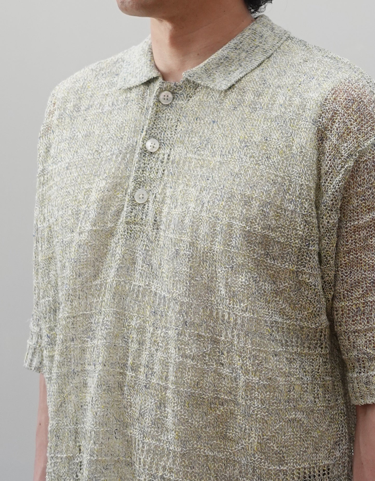 VOUILLON（ヴイヨン）のOpenwork Stitch Polo Linen Knit Shirt（オープンワークステッチポロリネンニットシャツ）。涼しげな透かし編み（オープンワーク）を施した、リネン素材のポロ襟ニットシャツ。独特の透け感とリラクシングなシルエットが特徴。モデル着用正面襟元画像。