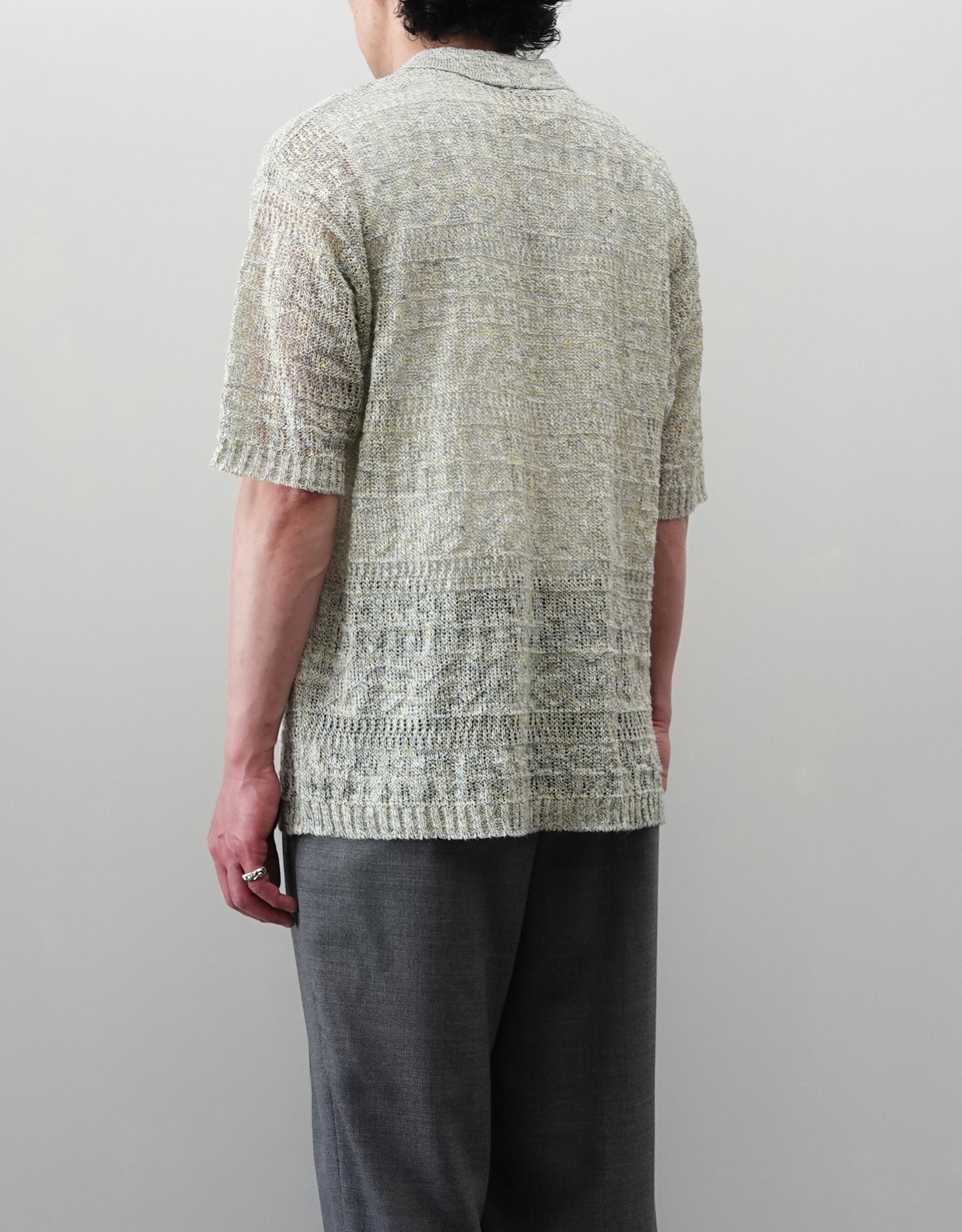 VOUILLON（ヴイヨン）のOpenwork Stitch Polo Linen Knit Shirt（オープンワークステッチポロリネンニットシャツ）。涼しげな透かし編み（オープンワーク）を施した、リネン素材のポロ襟ニットシャツ。独特の透け感とリラクシングなシルエットが特徴。モデル着用右後向き画像。