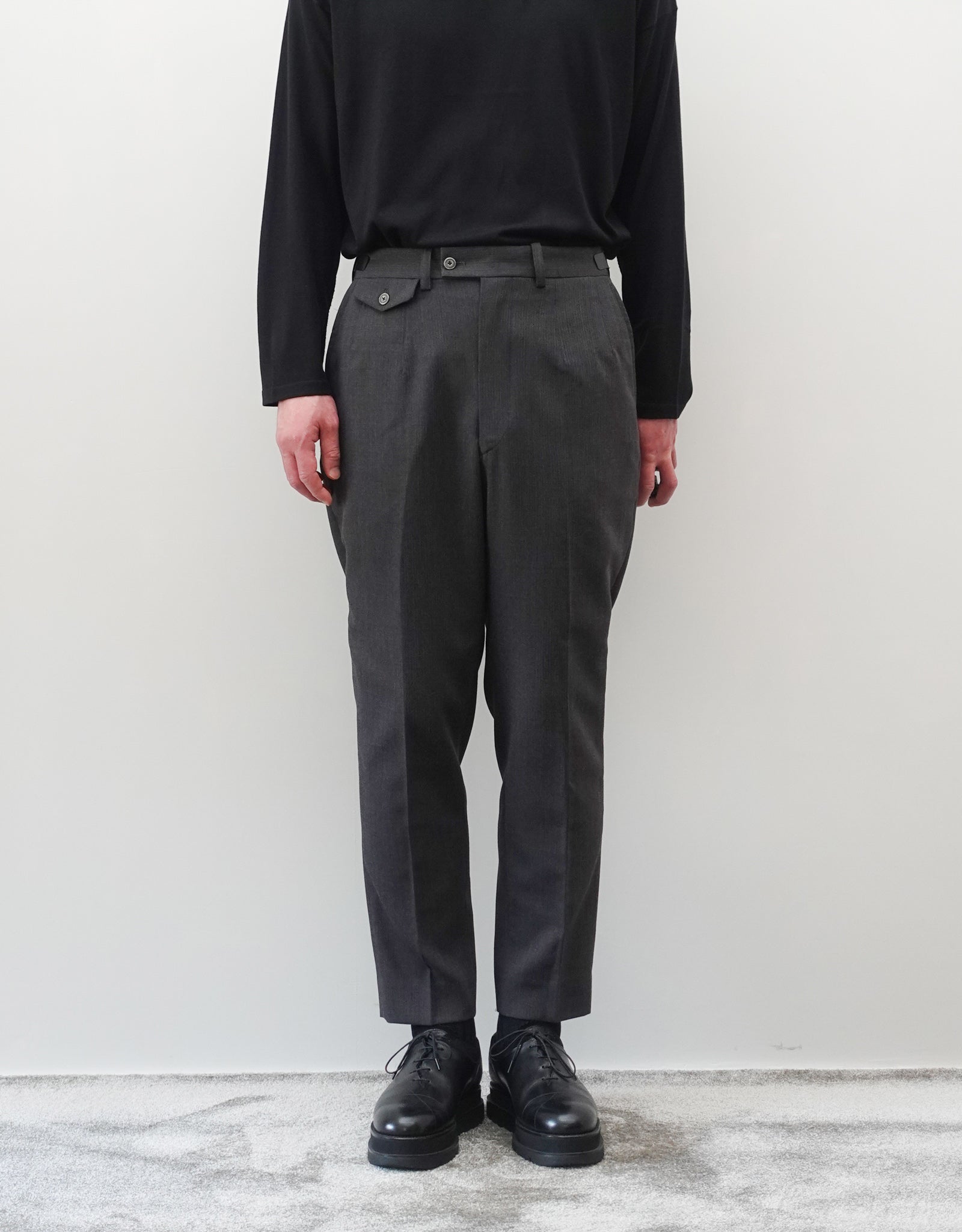 VOUILLON（ヴイヨン）のTwo Darts Slim Trousers - Gray Multi Stripe（2ダーツスリムトラウザーズ）。グレーマルチストライプ柄の端正な生地に、ウエスト回りをすっきり見せる2ダーツ仕様のスリムパンツ。美しいスリムテーパードシルエット。モデル着用正面画像。