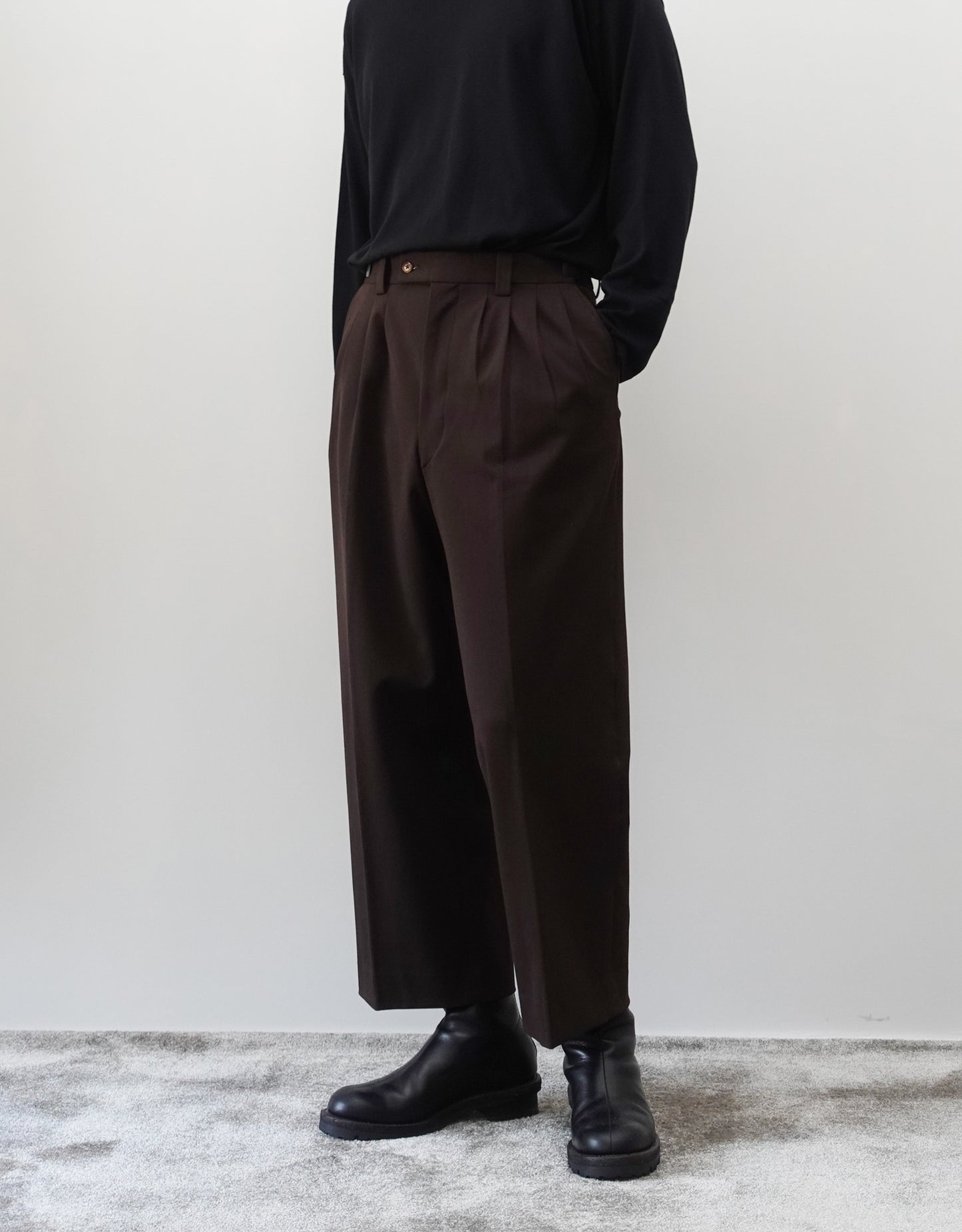 VOUILLON（ヴイヨン）のFour Pleats Wide Trousers - Dark Chocolate（4プリーツワイドトラウザーズ）。ダークチョコレート（深みのあるブラウン）のワイドシルエットと腰元の4プリーツ。モデルによる斜め向きの着用画像。