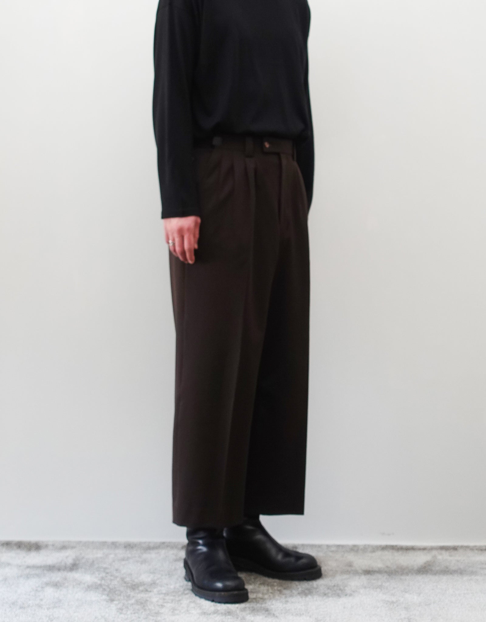 VOUILLON（ヴイヨン）のFour Pleats Wide Trousers - Dark Chocolate（4プリーツワイドトラウザーズ）。ダークチョコレート（深みのあるブラウン）のワイドシルエットと腰元の4プリーツ。モデルによる左斜め前向きの着用画像。