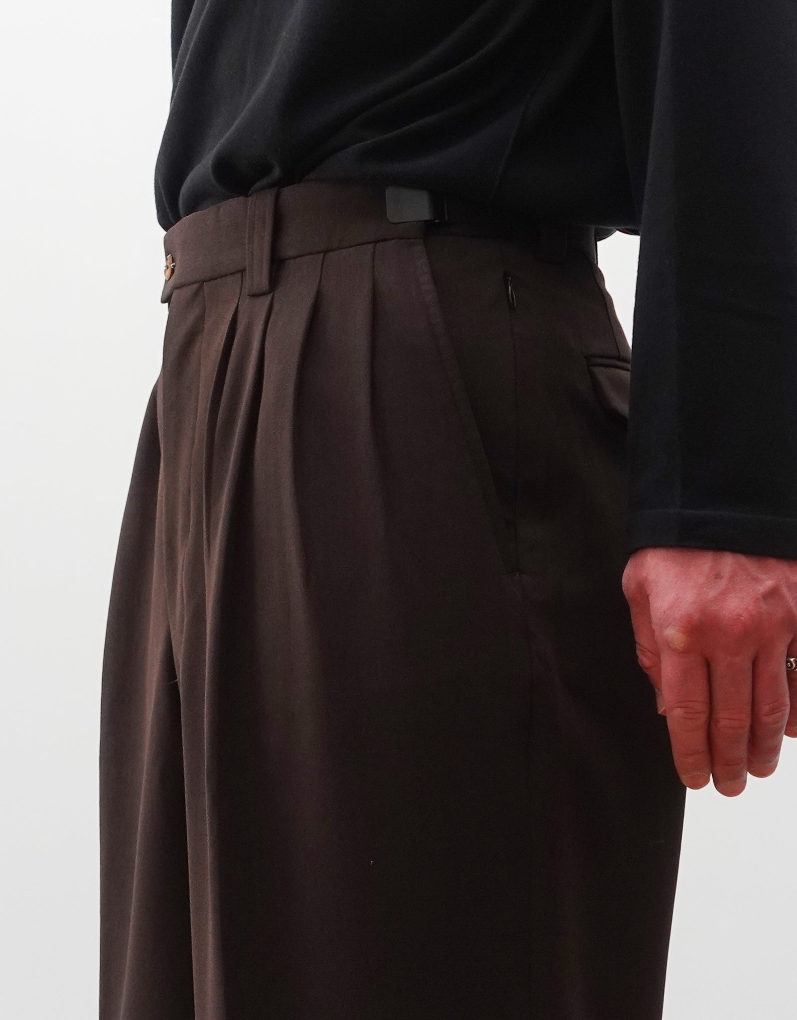 VOUILLON（ヴイヨン）のFour Pleats Wide Trousers - Dark Chocolate（4プリーツワイドトラウザーズ）。ダークチョコレート（深みのあるブラウン）のワイドシルエットと腰元の4プリーツ。モデルによる右斜め向きの着用画像のウエストアップ。