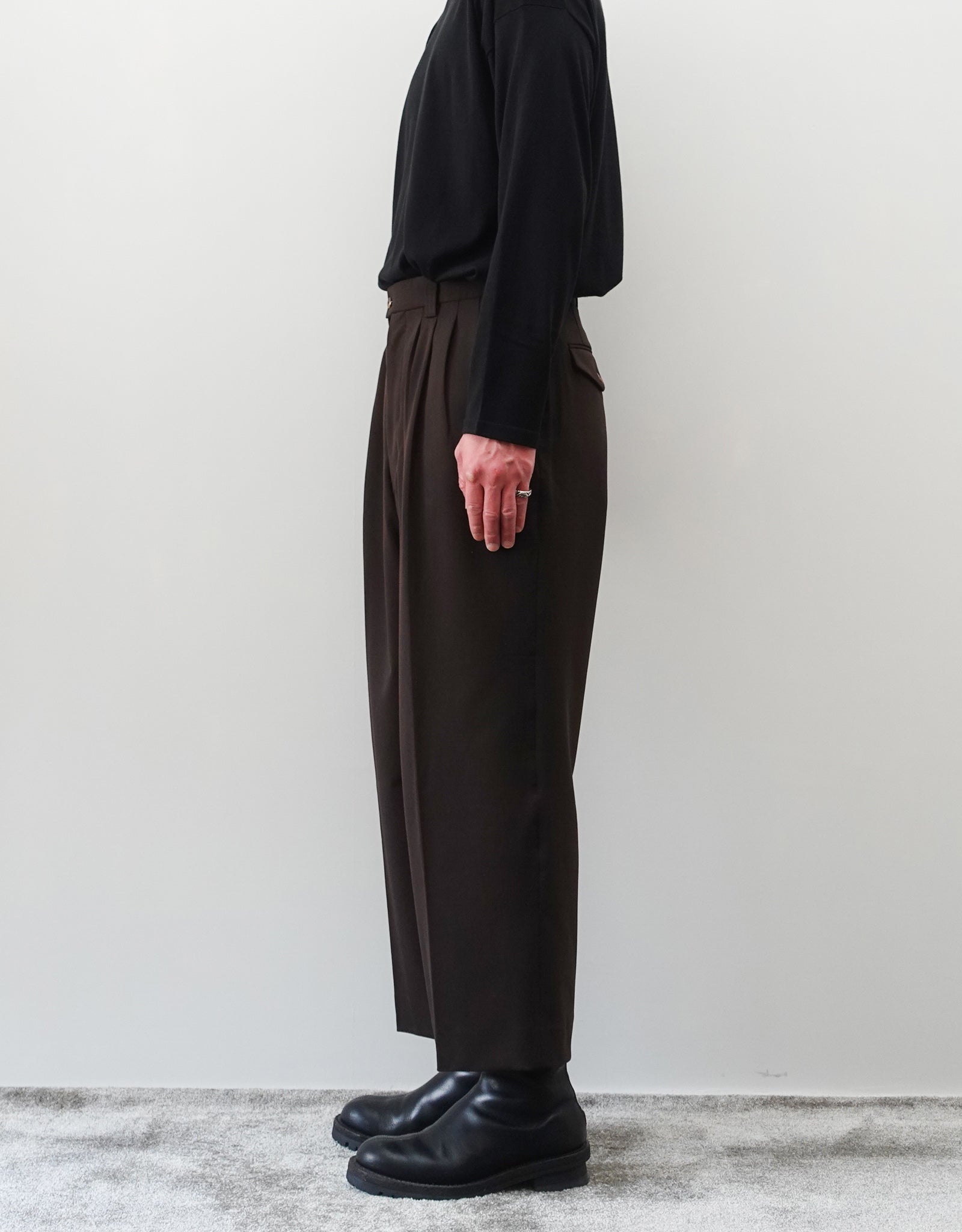 VOUILLON（ヴイヨン）のFour Pleats Wide Trousers - Dark Chocolate（4プリーツワイドトラウザーズ）。ダークチョコレート（深みのあるブラウン）のワイドシルエットと腰元の4プリーツ。モデルによる右向きの着用画像。