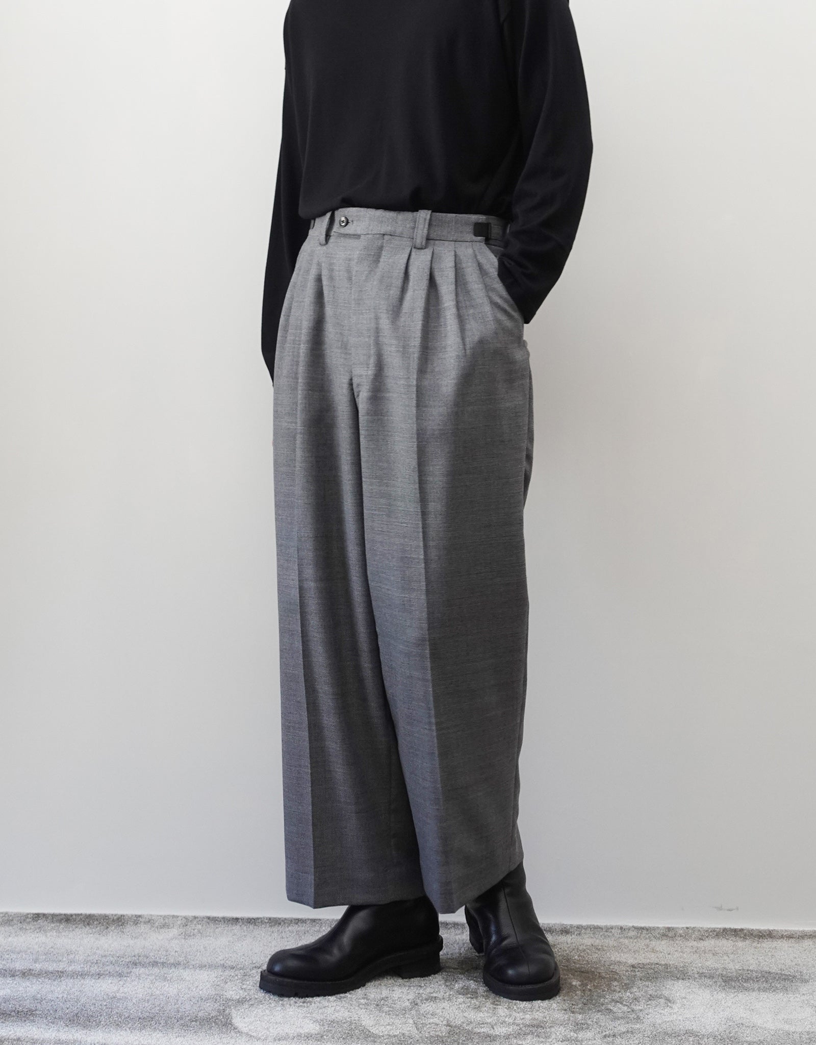 VOUILLON（ヴイヨン）のFour Pleats Wide Trousers - Gray（4プリーツワイドトラウザーズ）。ソリッドなグレーの生地に、腰元の4プリーツが深みのある陰影を生み出すワイドパンツ。洗練されたミニマルなスタイリング。モデル着用正面画像。