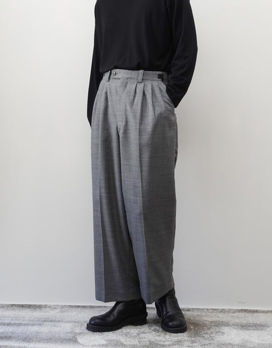 VOUILLON（ヴイヨン）のFour Pleats Wide Trousers - Gray（4プリーツワイドトラウザーズ）。ソリッドなグレーの生地に、腰元の4プリーツが深みのある陰影を生み出すワイドパンツ。洗練されたミニマルなスタイリング。モデル着用正面画像。