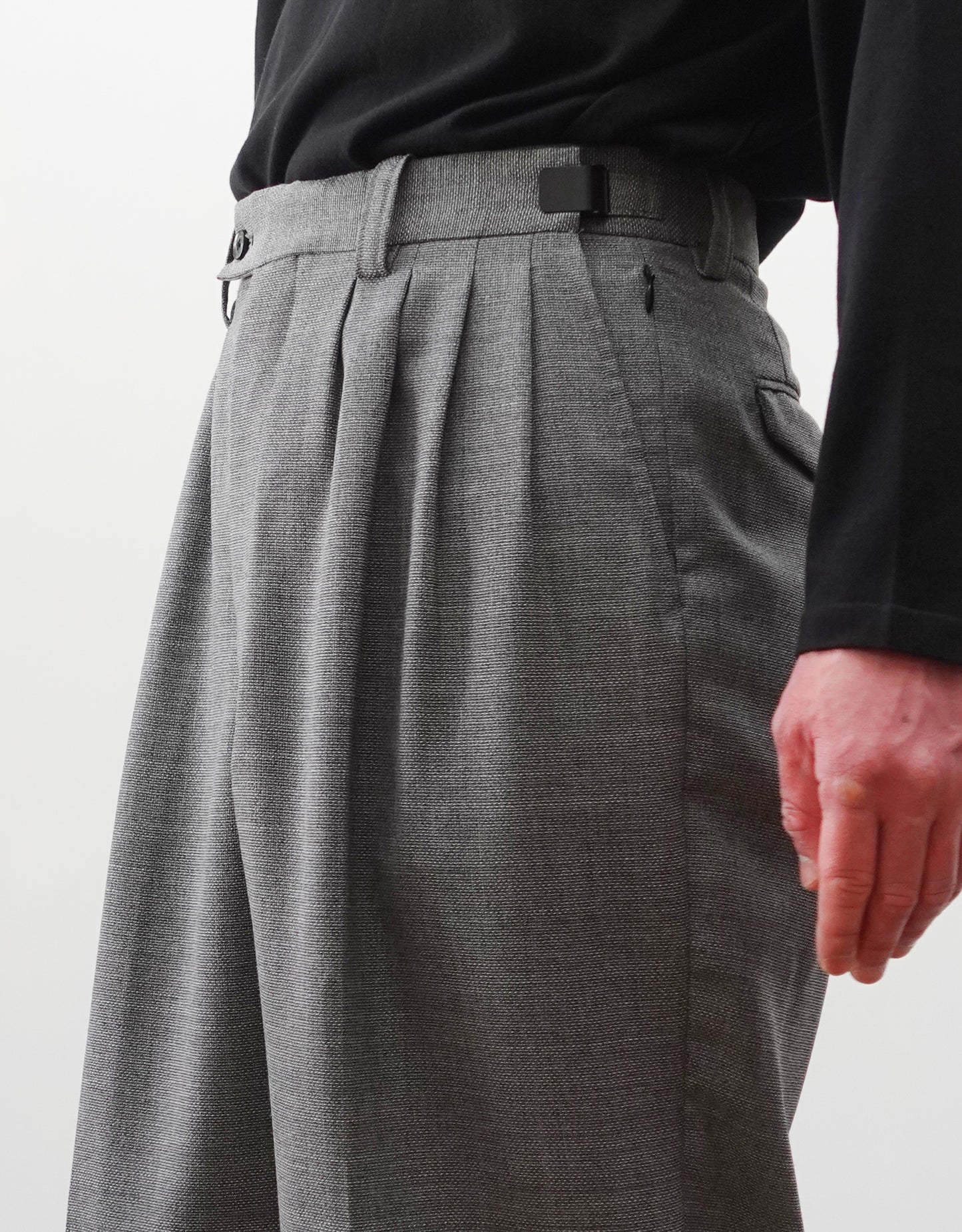 VOUILLON（ヴイヨン）のFour Pleats Wide Trousers - Gray（4プリーツワイドトラウザーズ）。ソリッドなグレーの生地に、腰元の4プリーツが深みのある陰影を生み出すワイドパンツ。洗練されたミニマルなスタイリング。モデル着用右向きウエストのフォープリーツアップ画像。