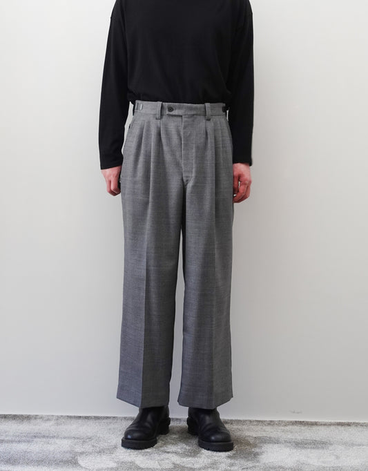 VOUILLON（ヴイヨン）のFour Pleats Wide Trousers - Gray（4プリーツワイドトラウザーズ）。ソリッドなグレーの生地に、腰元の4プリーツが深みのある陰影を生み出すワイドパンツ。洗練されたミニマルなスタイリング。モデル着用正面画像。