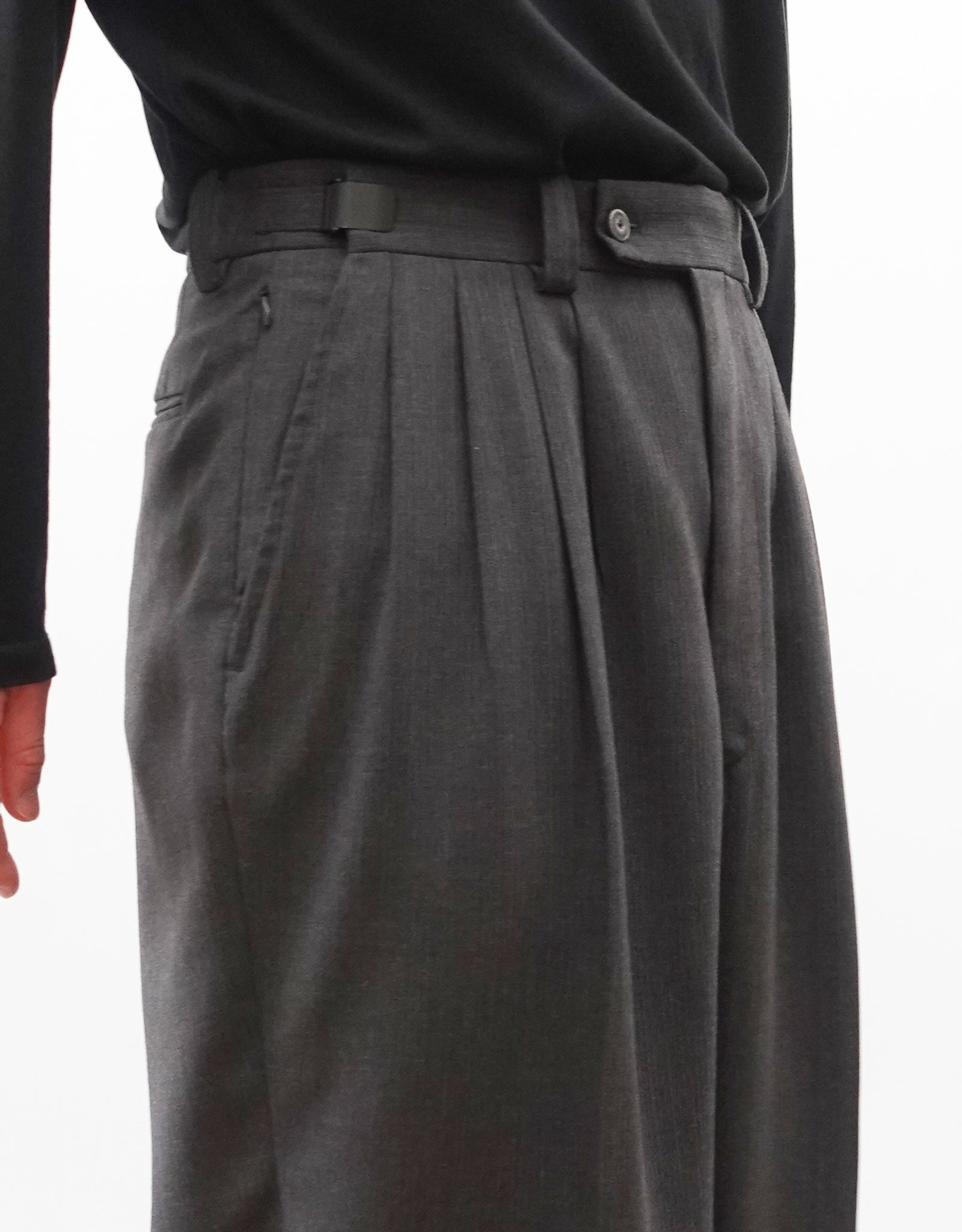 VOUILLON（ヴイヨン）のFour Pleats Wide Trousers - Gray Multi Stripe（4プリーツワイドトラウザーズ）。グレー地にマルチストライプを配した、4プリーツ仕様のワイドパンツ。ストライプによる脚長効果と立体的なシルエットが特徴。モデル着用左向きウエストアップ画像。