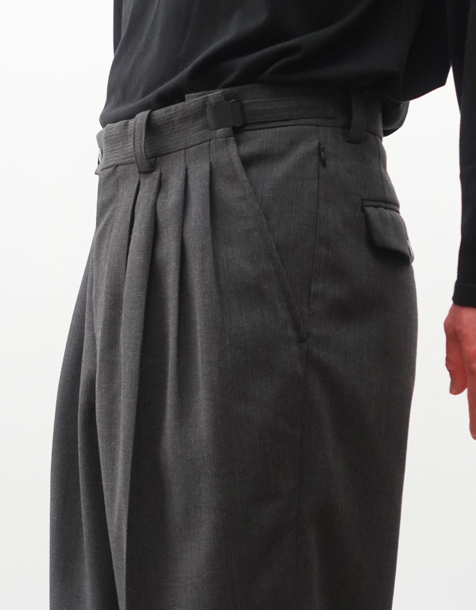 VOUILLON（ヴイヨン）のFour Pleats Wide Trousers - Gray Multi Stripe（4プリーツワイドトラウザーズ）。グレー地にマルチストライプを配した、4プリーツ仕様のワイドパンツ。ストライプによる脚長効果と立体的なシルエットが特徴。モデル着用ウエストアップ右向き（アジャスター最大開き）画像。