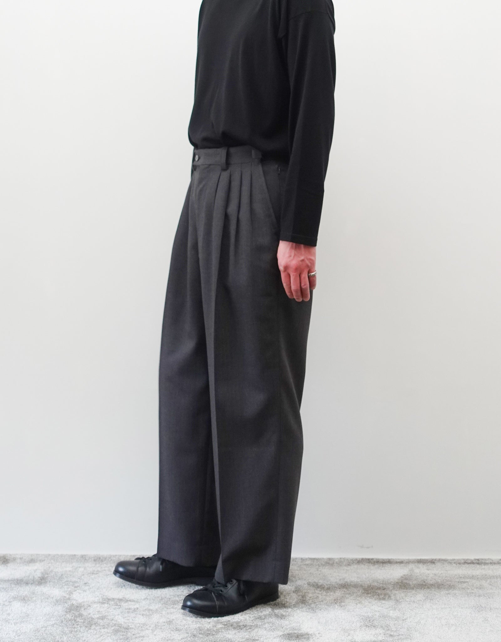VOUILLON（ヴイヨン）のFour Pleats Wide Trousers - Gray Multi Stripe（4プリーツワイドトラウザーズ）。グレー地にマルチストライプを配した、4プリーツ仕様のワイドパンツ。ストライプによる脚長効果と立体的なシルエットが特徴。モデル着用右向き画像。