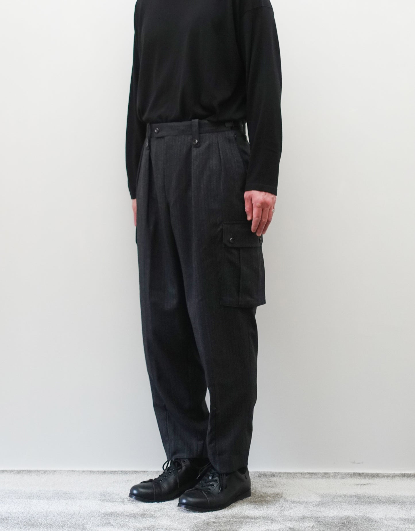 VOUILLON（ヴイヨン）のTwo Tuck Cargo Slacks - chacoal Stripe（2タックカーゴスラックス - チャコールストライプ）。上質な生地で立体的に仕上げることでシルエットの美しさとカーゴポケットの機能性の両立させたカーゴパンツ。モデル着用正面画像。
