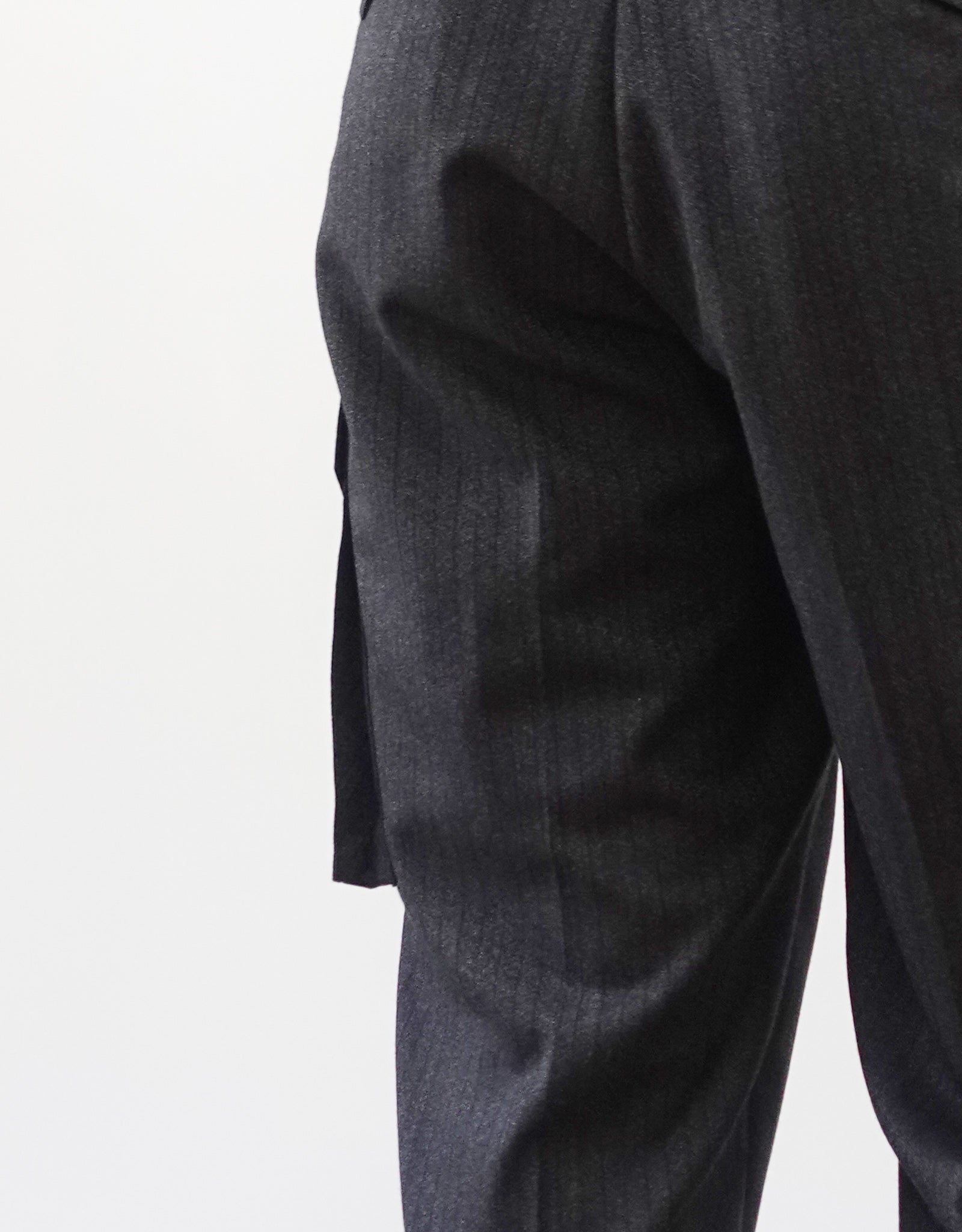 VOUILLON（ヴイヨン）のTwo Tuck Cargo Slacks - chacoal Stripe（2タックカーゴスラックス - チャコールストライプ）。上質な生地で立体的に仕上げることでシルエットの美しさとカーゴポケットの機能性の両立させたカーゴパンツ。モデル着用左斜め後向きカー後ポケット画像。