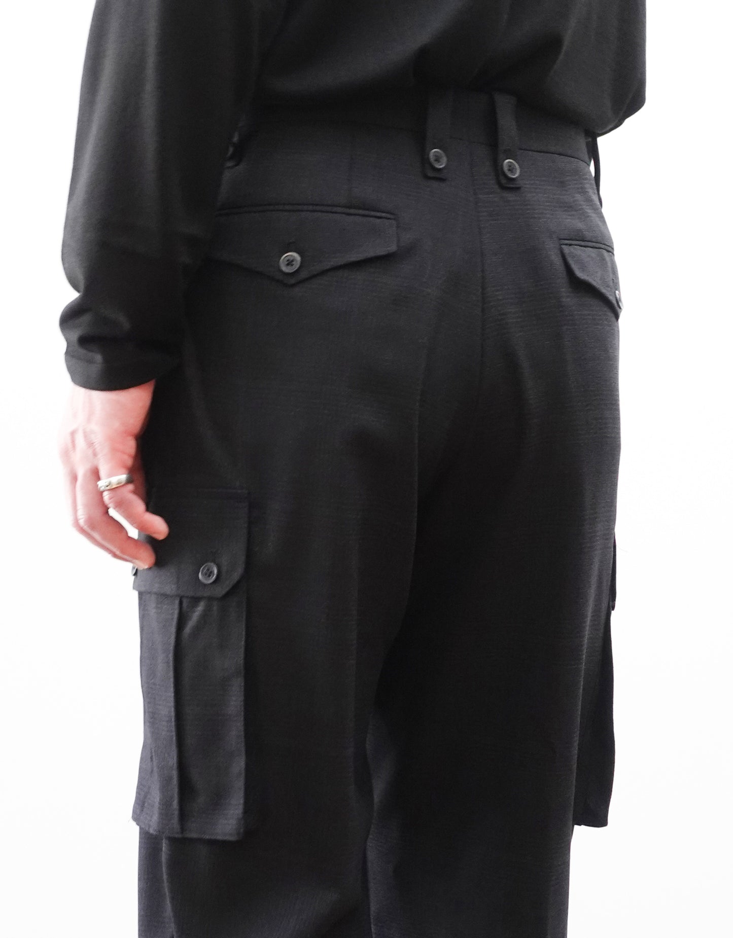 VOUILLON（ヴイヨン）のTwo Tuck Cargo Slacks - Black Glen Check（ツータックカーゴスラックス）。黒を基調としたシックなグレンチェック柄生地に、腰元のツータックと上品なサイドポケットを配したモードなカーゴパンツ。モデル着用左後腰を写した画像。