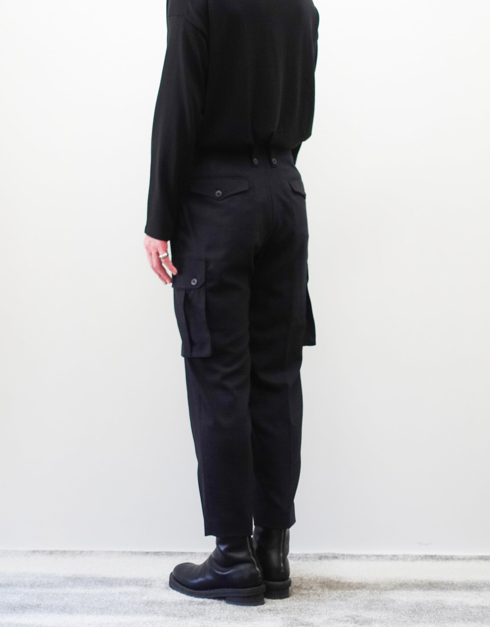 VOUILLON（ヴイヨン）のTwo Tuck Cargo Slacks - Black Glen Check（ツータックカーゴスラックス）。黒を基調としたシックなグレンチェック柄生地に、腰元のツータックと上品なサイドポケットを配したモードなカーゴパンツ。モデル着用右後向き画像。