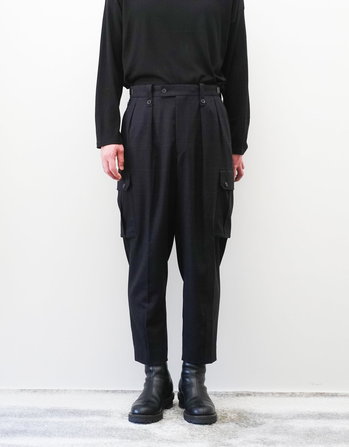 VOUILLON（ヴイヨン）のTwo Tuck Cargo Slacks - Black Glen Check（ツータックカーゴスラックス）。黒を基調としたシックなグレンチェック柄生地に、腰元のツータックと上品なサイドポケットを配したモードなカーゴパンツ。モデル着用正面画像。