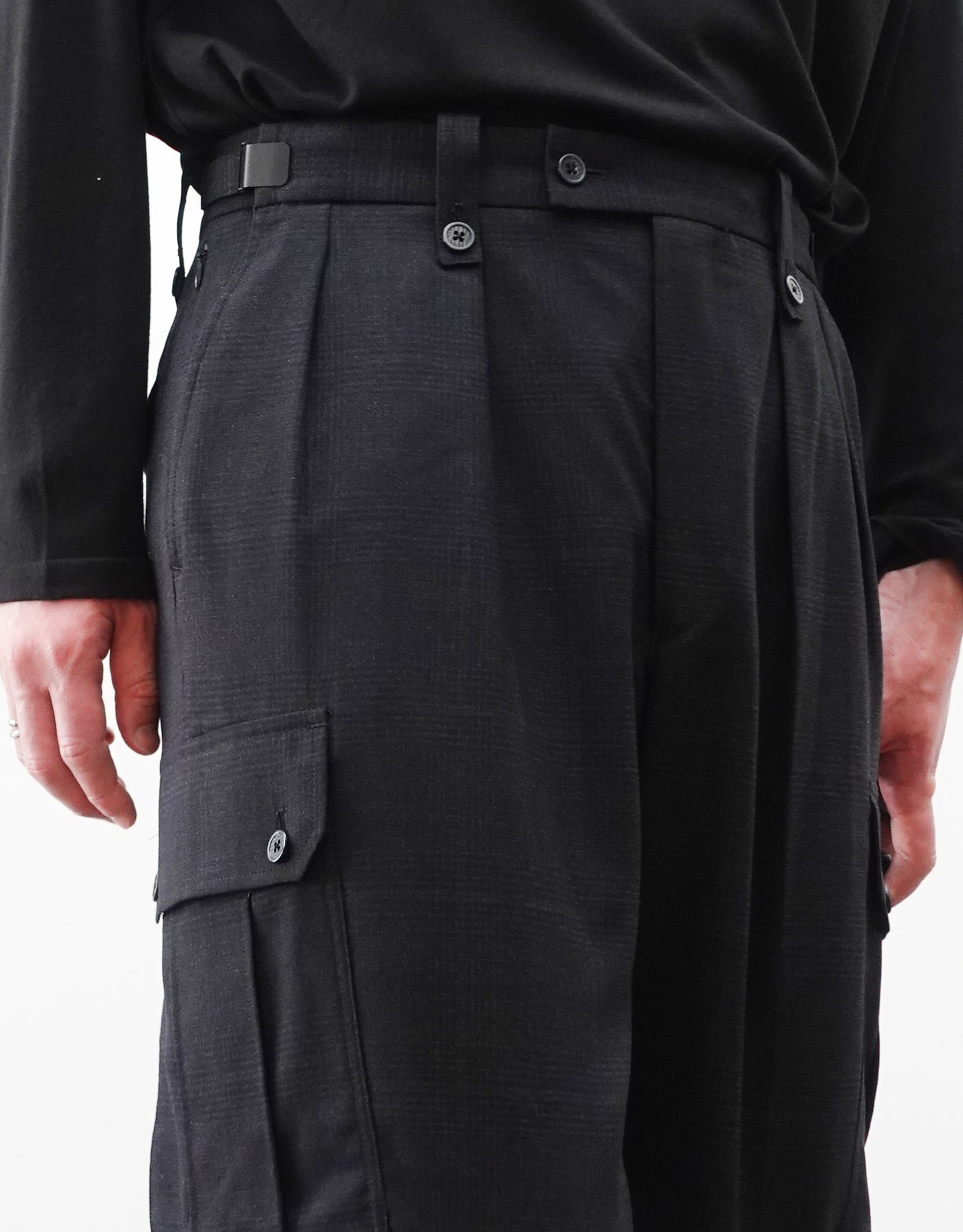 VOUILLON（ヴイヨン）のTwo Tuck Cargo Slacks - Black Glen Check（ツータックカーゴスラックス）。黒を基調としたシックなグレンチェック柄生地に、腰元のツータックと上品なサイドポケットを配したモードなカーゴパンツ。モデル着用右腰のタックを写した画像。