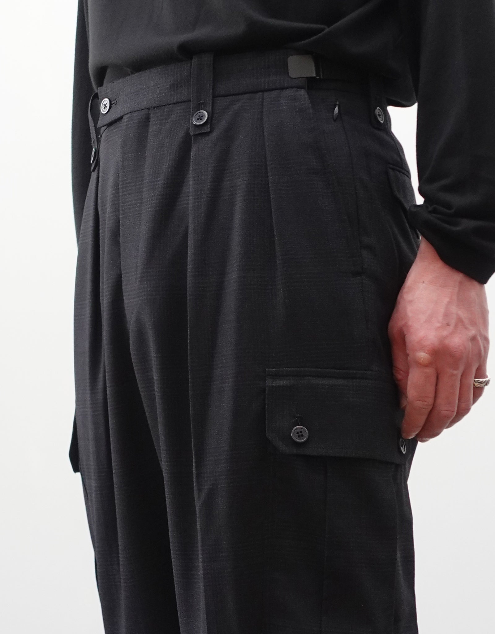 VOUILLON（ヴイヨン）のTwo Tuck Cargo Slacks - Black Glen Check（ツータックカーゴスラックス）。黒を基調としたシックなグレンチェック柄生地に、腰元のツータックと上品なサイドポケットを配したモードなカーゴパンツ。モデル着用左腰を写した画像。